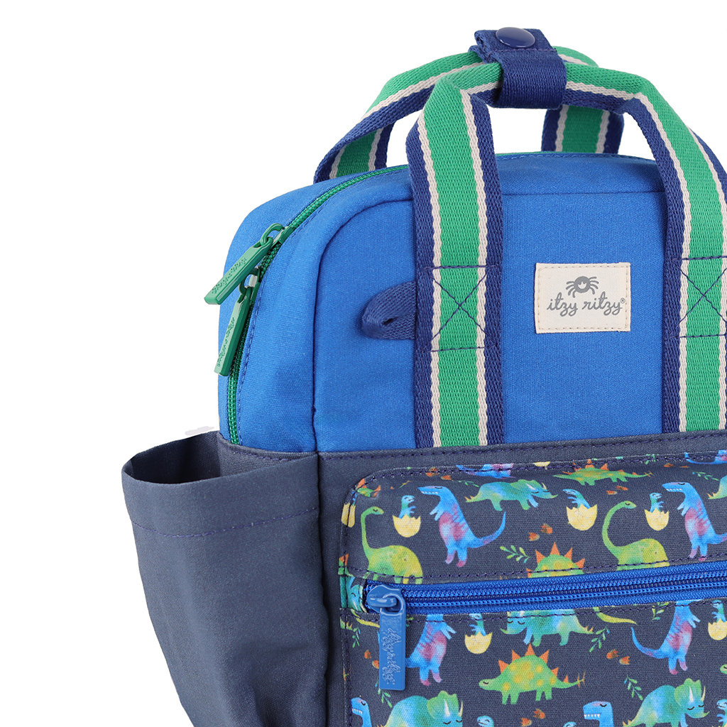 101601542 Itzy Bitzy Bag™ Toddler Backpack - Raining Dinos (1) Introducing the Itzy Ritzy Sweetie Strap Plus Bear Silicone Pacifier Clip: a delightful blue and green children's accessory featuring colorful dinosaur patterns on the front pocket, a side water bottle pocket, and striped handles.