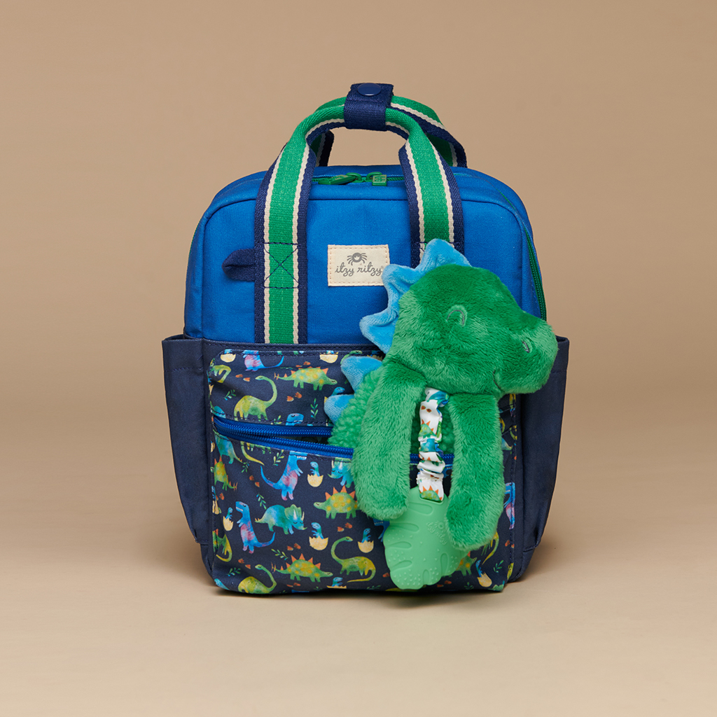 101601542 Itzy Bitzy Bag™ Toddler Backpack - Raining Dinos (6) A blue and green children's backpack featuring a dinosaur design, with an attached plush toy similar to the Itzy Ritzy Sweetie Strap Plus Bear Silicone Pacifier Clip.