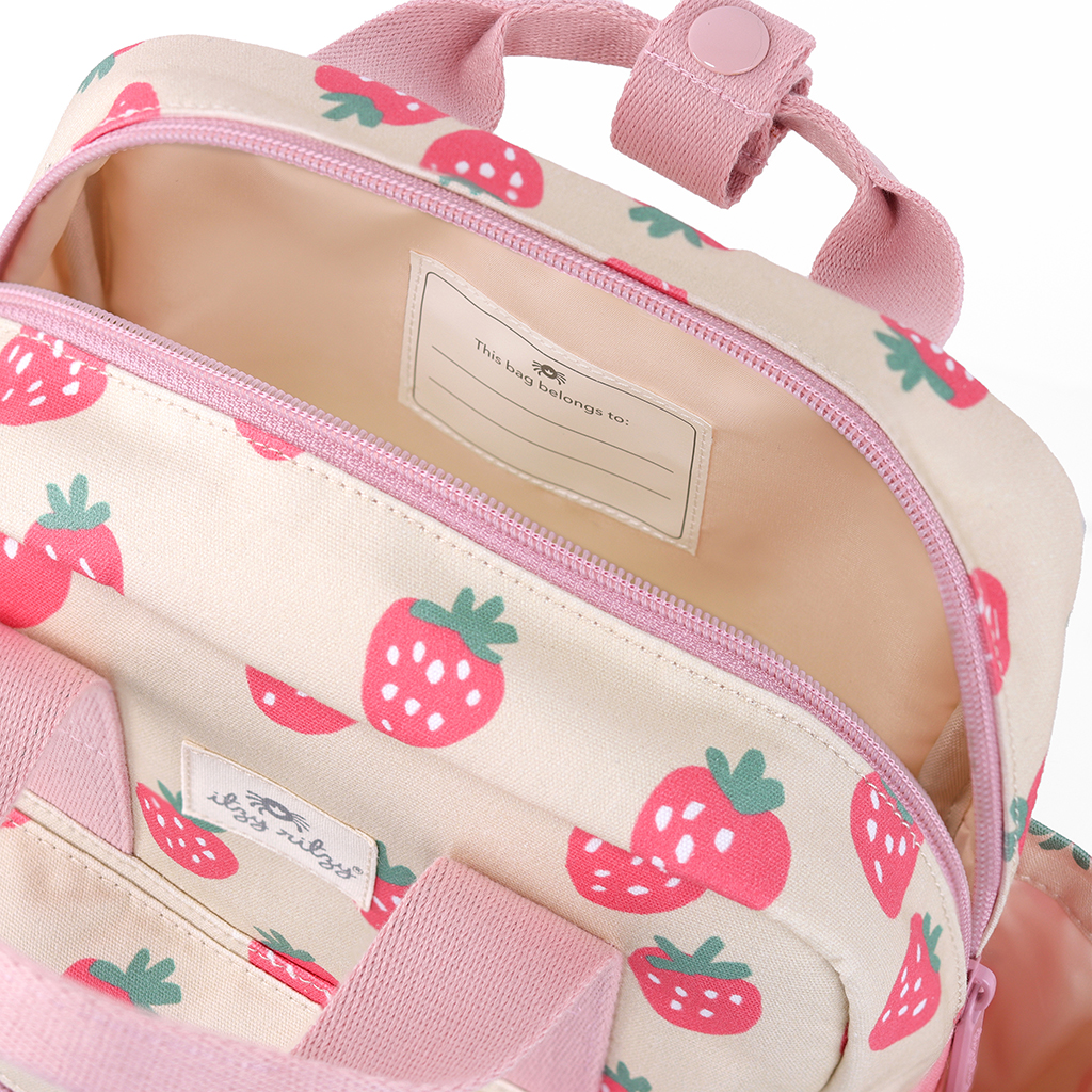 101601543 Itzy Bitzy Bag™ Toddler Backpack - Strawberries & Cream (15) The Itzy Ritzy Sweetie Strap Plus Bear Silicone Pacifier Clip, adorned with pink strawberry prints and featuring pink straps and a top handle, opens to reveal a name tag inside.