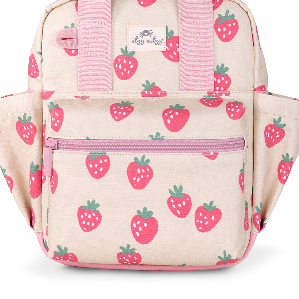 101601543 Itzy Bitzy Bag™ Toddler Backpack - Strawberries & Cream (5) A stylish Itzy Ritzy Sweetie Strap Plus Bear Silicone Pacifier Clip in beige, featuring pink straps, a zipper pocket, and an adorable strawberry pattern.