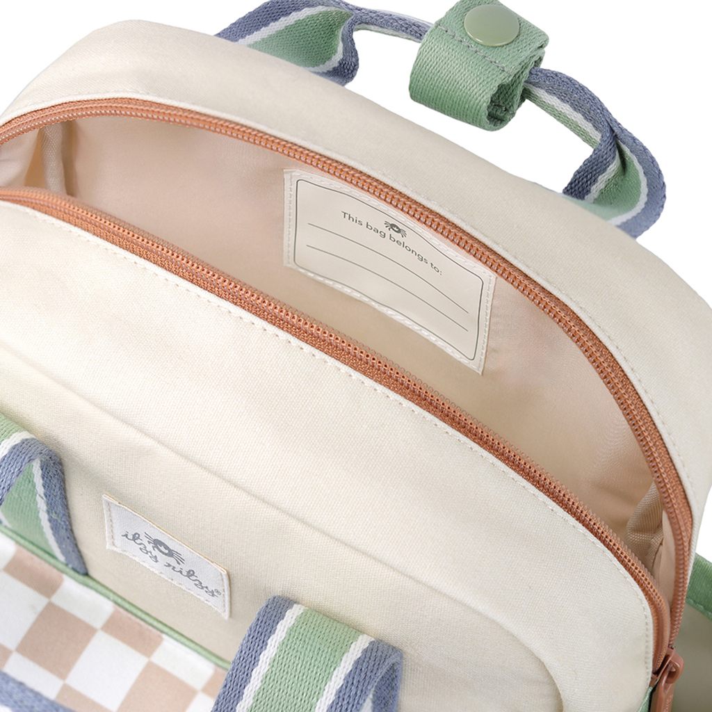101601544 Itzy Bitzy Bag™ Toddler Backpack - Check Yes! (18) The Itzy Ritzy Sweetie Strap Plus Bear Silicone Pacifier Clip, featuring a cream-colored design with a beige zipper that's partially open to reveal an inner pocket labeled "This bag belongs to" with space for personalization. The handle and trim come with stylish green and blue accents.