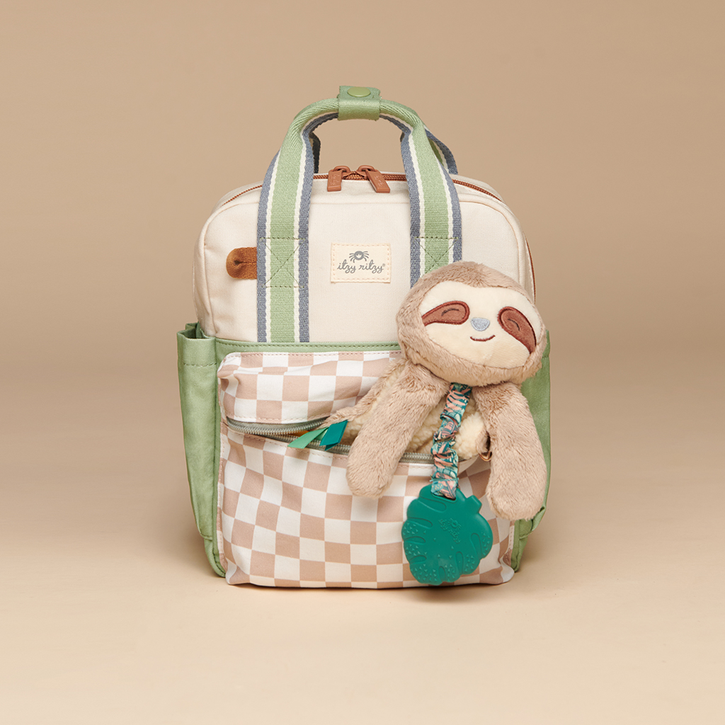 101601544 Itzy Bitzy Bag™ Toddler Backpack - Check Yes! A beige and green "Itzy Ritzy Sweetie Strap Plus Bear Silicone Pacifier Clip" featuring a checkered front pocket and a stuffed sloth toy attached to the zipper, set against a neutral background.