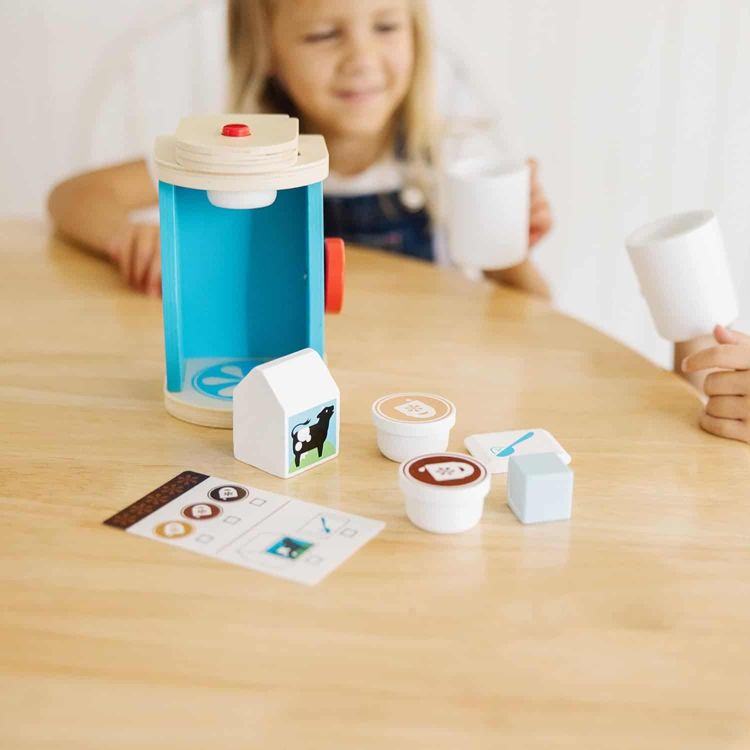 Melissa & Doug Brew & Serve Wooden Coffee Maker Set (Play Kitchen Accessories, Encourages Imaginative Play, A little girl is playing with a Melissa & Doug Brew and Serve Wooden Coffee Maker Set.
