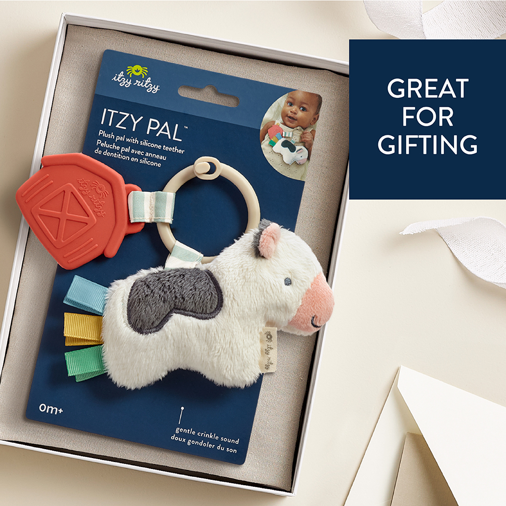 231220_Itzy_Ritzy_Digital_Shelf_ItzyPalCow A baby toy set featuring a plush toy with a silicone teether attached, packaged in a cardboard box. The package includes a small photo of a baby holding the toy and text that says "Great for gifting.