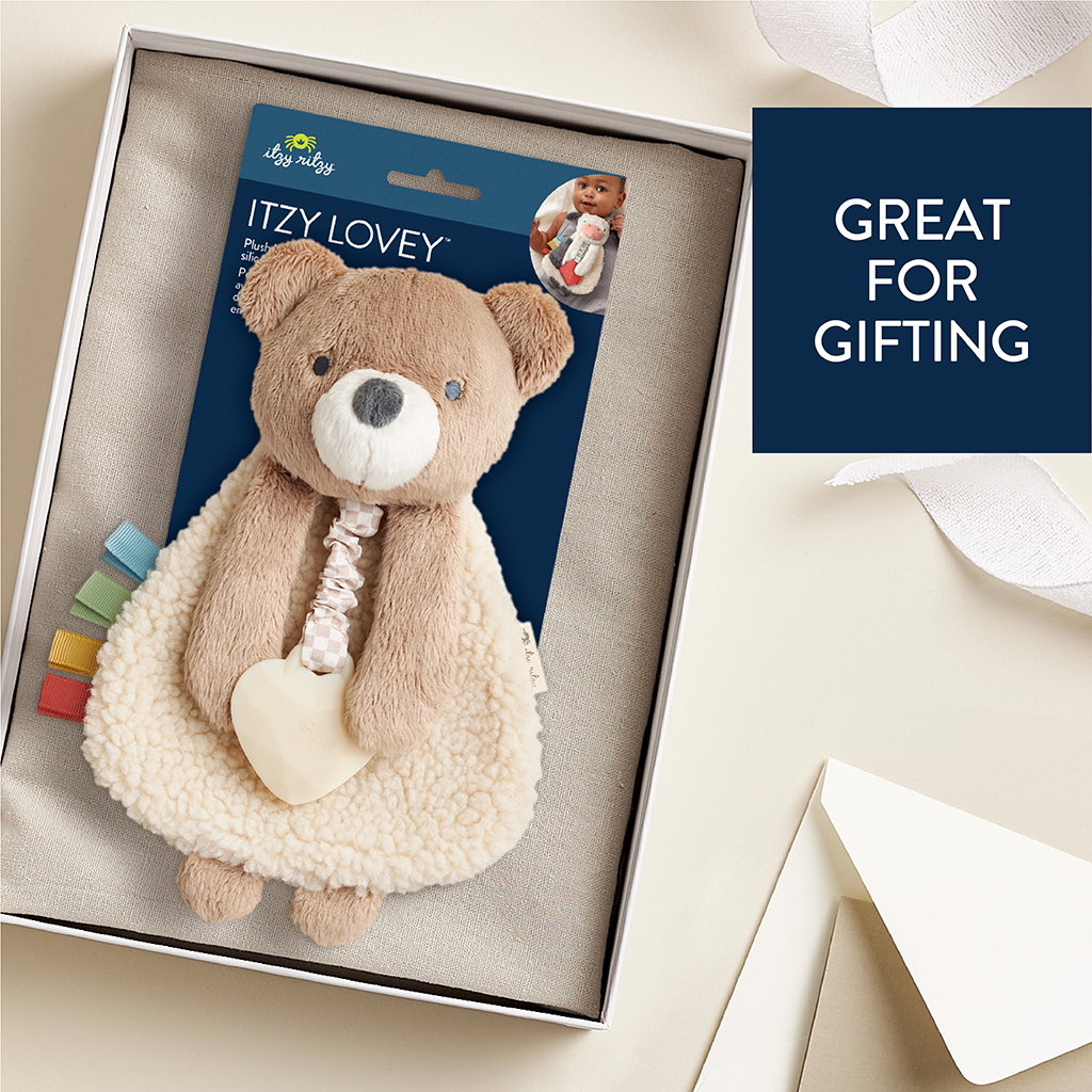 302801667_Itzy_Ritzy_Itzy_Lovey_Bear A plush teddy bear blanket with colorful tabs, packaged in a box. A tag reads "Itzy Lovey." A label on the side reads "Great for Gifting.