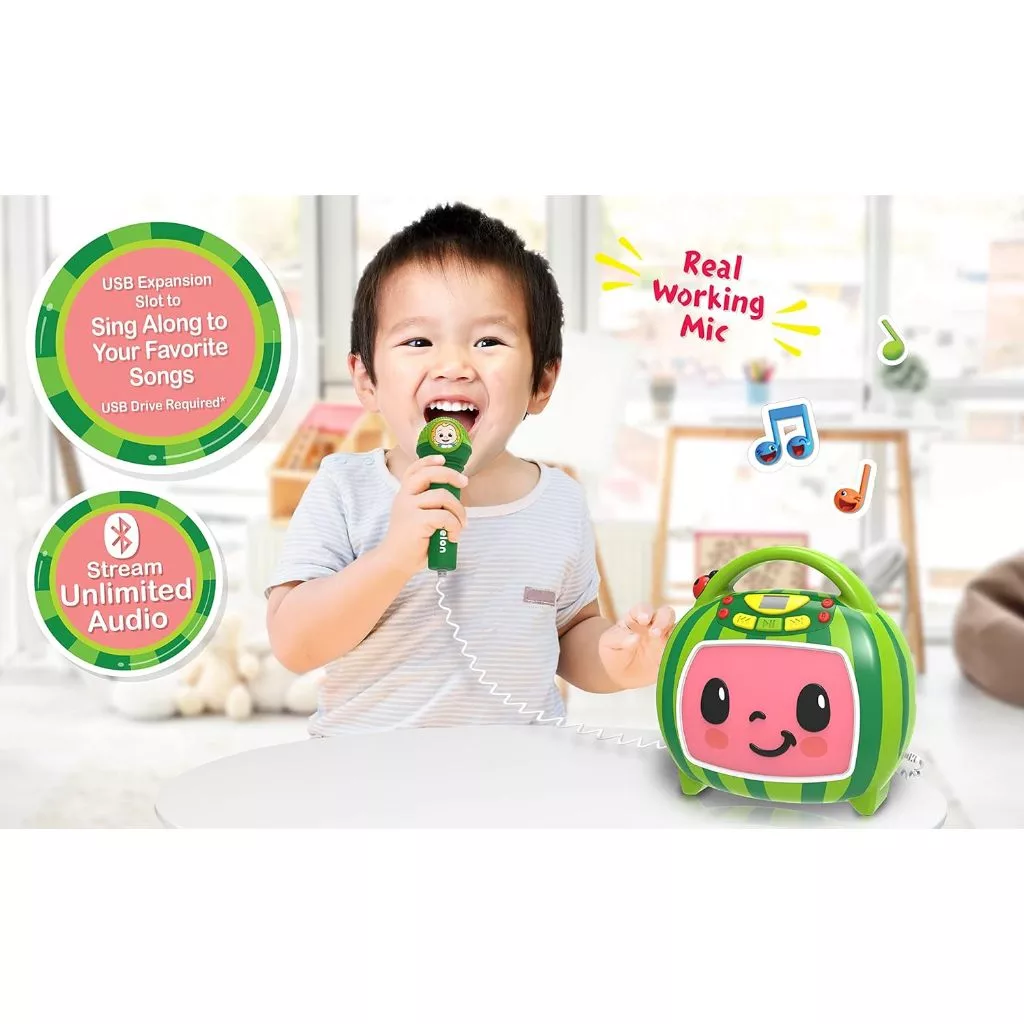 CoComelon Bluetooth MP3 Player Sing-Along Boombox Speaker With Karaoke Microphone USB Toddler Kids (7) A child sings into a microphone connected to a green-themed toy featuring a face. Text on the image highlights USB expansion for songs and audio streaming capabilities.