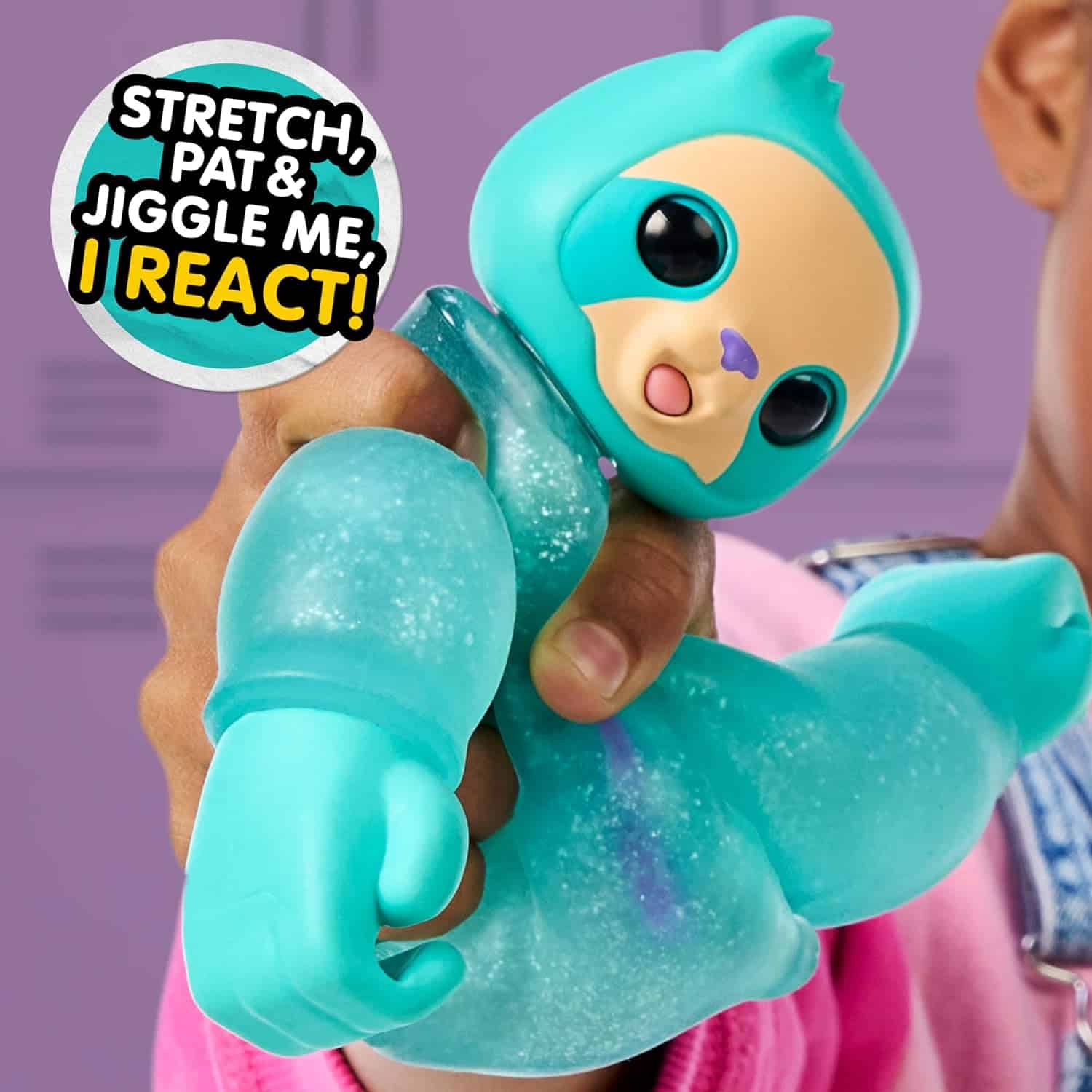 Little Live Pets Hug n' Hang Zoogooz - Sensoo Sloth. an Interactive Electronic Squishy Stretchy Toy Pet with 70+ Sounds & Reactions. Stretch, Squish and Link Their Hands (9) A person holding a blue, stretchy toy resembling an animal, with a speech bubble saying, "Stretch, Pat & Jiggle Me, I React!" in the background.