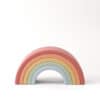 A pastel-colored wooden rainbow toy with six arches, arranged in descending size order against a light background.