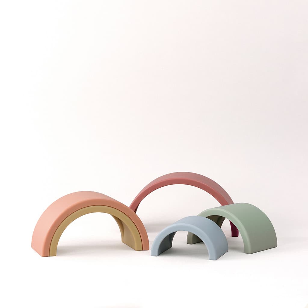 RS8548 Itzy Ritzy Rainbow Stacking Toy (6) Three colorful wooden arches in pastel shades arranged in a playful, overlapping composition on a plain background.
