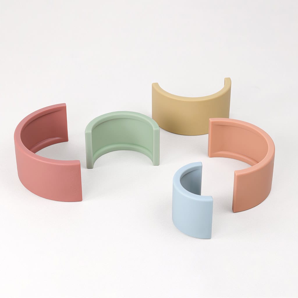 RS8548 Itzy Ritzy Rainbow Stacking Toy (7) Five pastel-colored, semicircular, plastic bracelet organizers displayed against a plain white background.