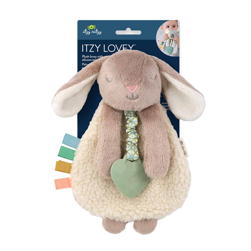 itzy-ritzy-302801555-itzy-lovey-taupe-bunny-1 Plush bunny stuffed toy with a green heart-shaped teether, attached colored ribbons, and packaged in branded cardboard with a baby photo.