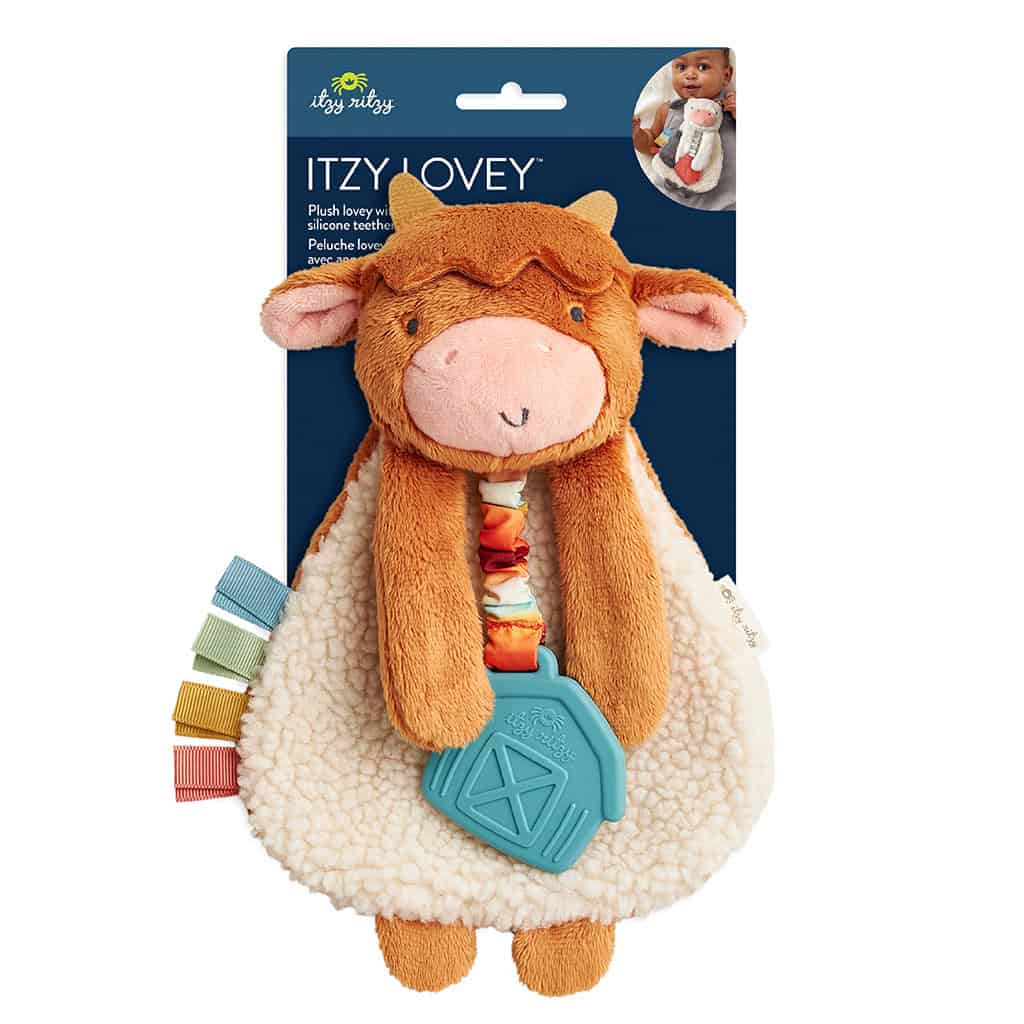 302801668_Itzy_Ritzy_Itzy_Lovey_Highland_Cow A brown plush toy shaped like a cow with a blue teething ring attached, various colored tags on the side, and a packaging label that reads "Itzy Lovey.