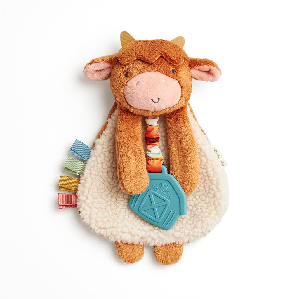 302801668_Itzy_Ritzy_Itzy_Lovey_Highland_Cow Plush toy shaped like a cow with a soft beige body, brown head, and ears. Attached to it is a blue teething toy and colorful fabric tabs on one side. Ideal for infants and toddlers.