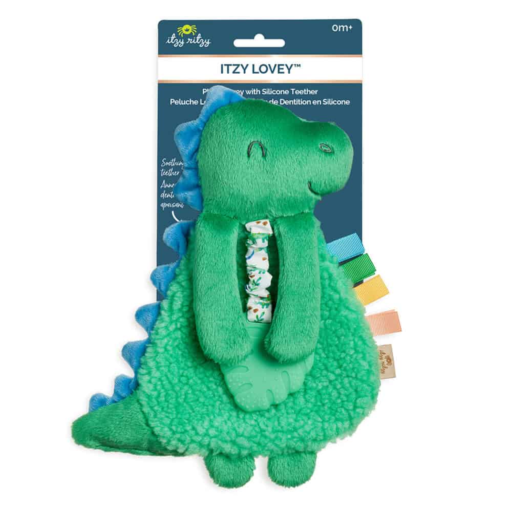 Green and blue dinosaur plush toy with silicone teether, featuring a patterned ribbon and colorful tags. The packaging is labeled "Itzy Lovey" by Itzy Ritzy, suitable for ages 0+.