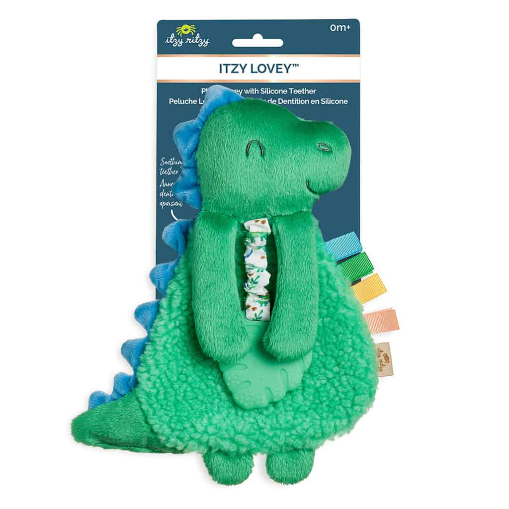 itzy-ritzy-lov8085-itzy-lovey-green-dino-1 Green and blue dinosaur plush toy with silicone teether, featuring a patterned ribbon and colorful tags. The packaging is labeled "Itzy Lovey" by Itzy Ritzy, suitable for ages 0+.