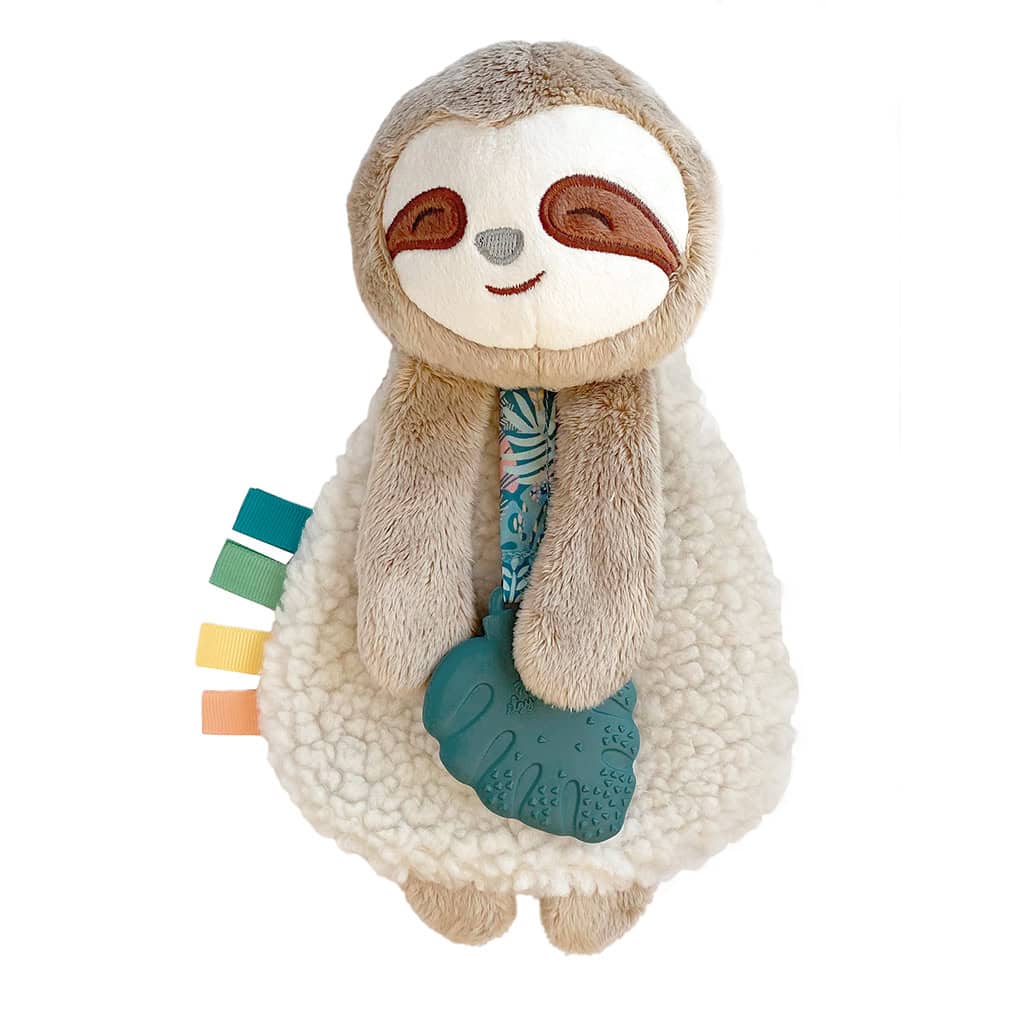 itzy-ritzy-lov8317-itzy-lovey-sloth-1 A plush sloth toy holding a textured blue leaf teether, with colorful tags on its side, against a white background.