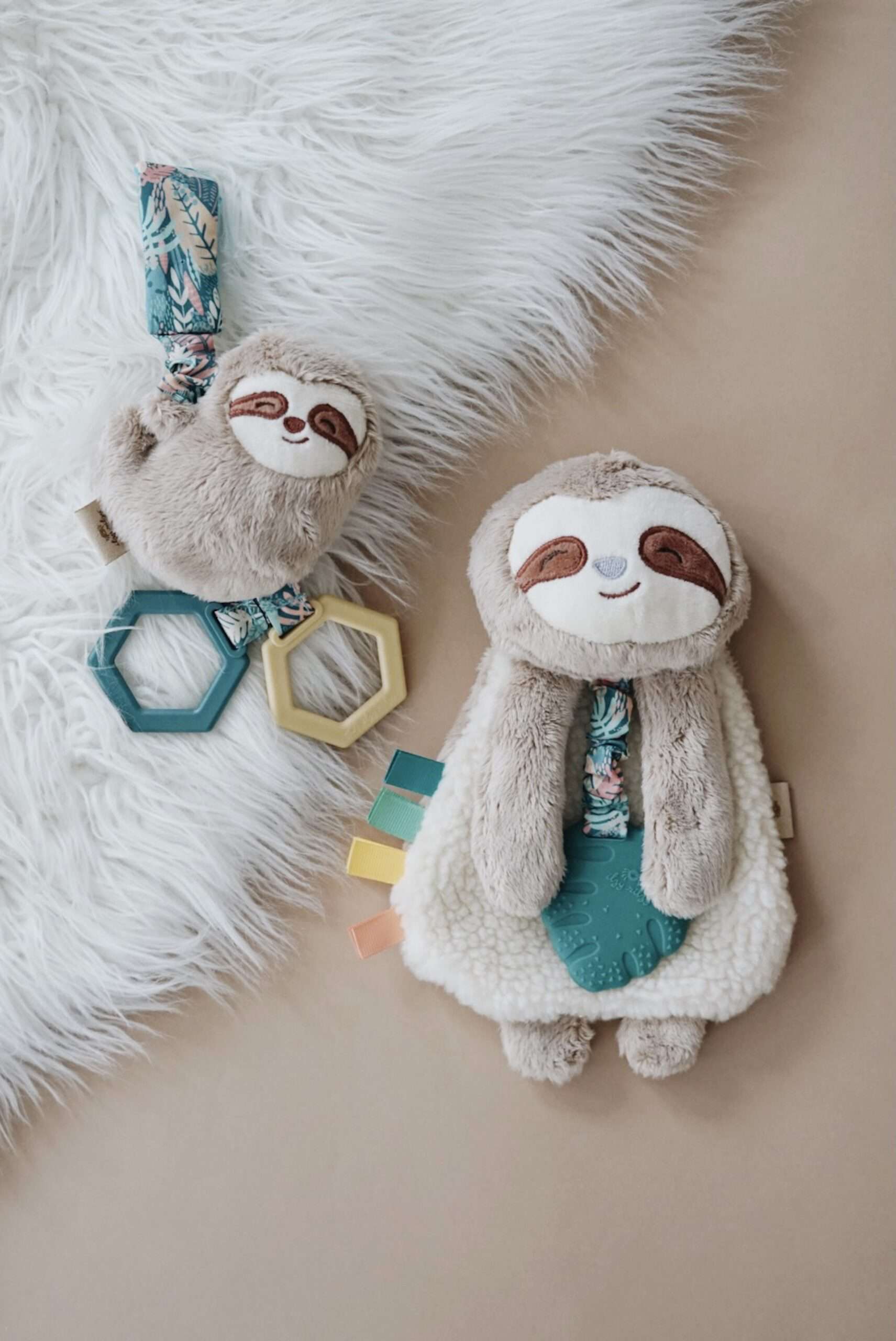 Processed with VSCO with a6 preset Plush sloth toys with hexagonal teething rings on a light surface; one smaller toy has two rings, and a larger toy has three attached fabric tags.