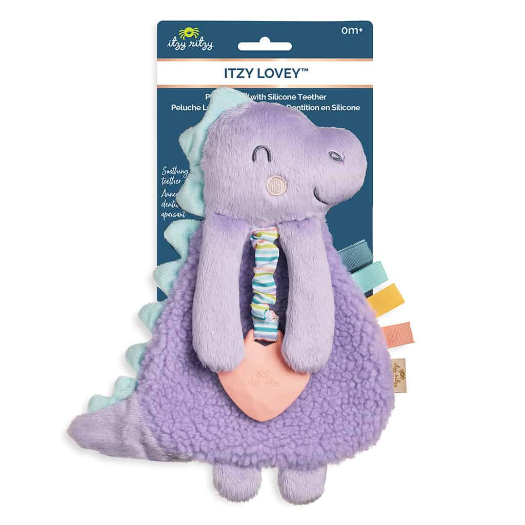 itzy-ritzy-lov8430-itzy-lovey-purple-dino-5 A plush dinosaur baby toy, its brand "Itzy Ritzy" visible on the packaging. The toy features a textured silicone teether and colorful ribbon tags on the side, suitable for ages 0 months and up.