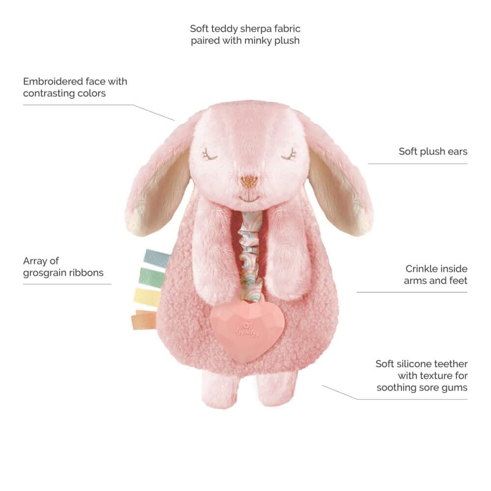 Plush pink bunny toy with embroidered face, soft plush ears, crinkle arms and feet, an array of grosgrain ribbons, and a soft silicone teether attached to a rattle heart.