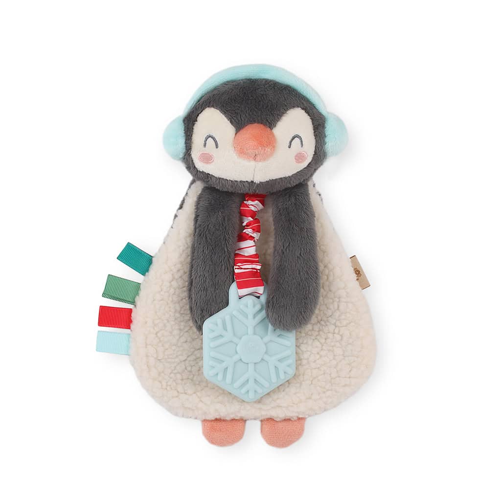 itzy-ritzy-lov8503-itzy-lovey-holiday-north-the-pengui A plush penguin toy with red, green, and blue ribbon tags, wearing blue earmuffs and holding a blue snowflake teether.