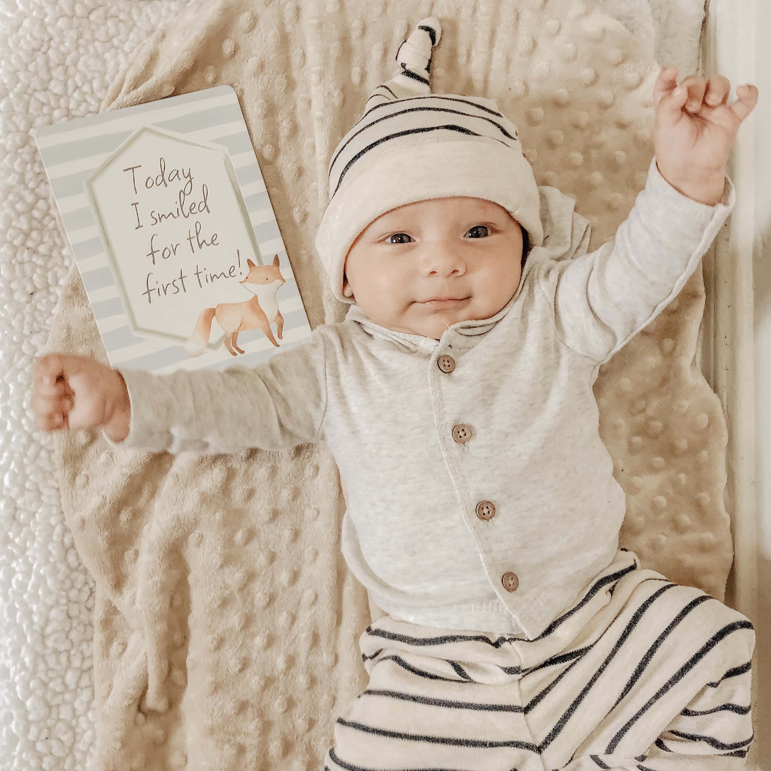 itzy-ritzy-mc8383-itzy-moments-woodland-6 A baby is laying on a blanket with a teddy bear.