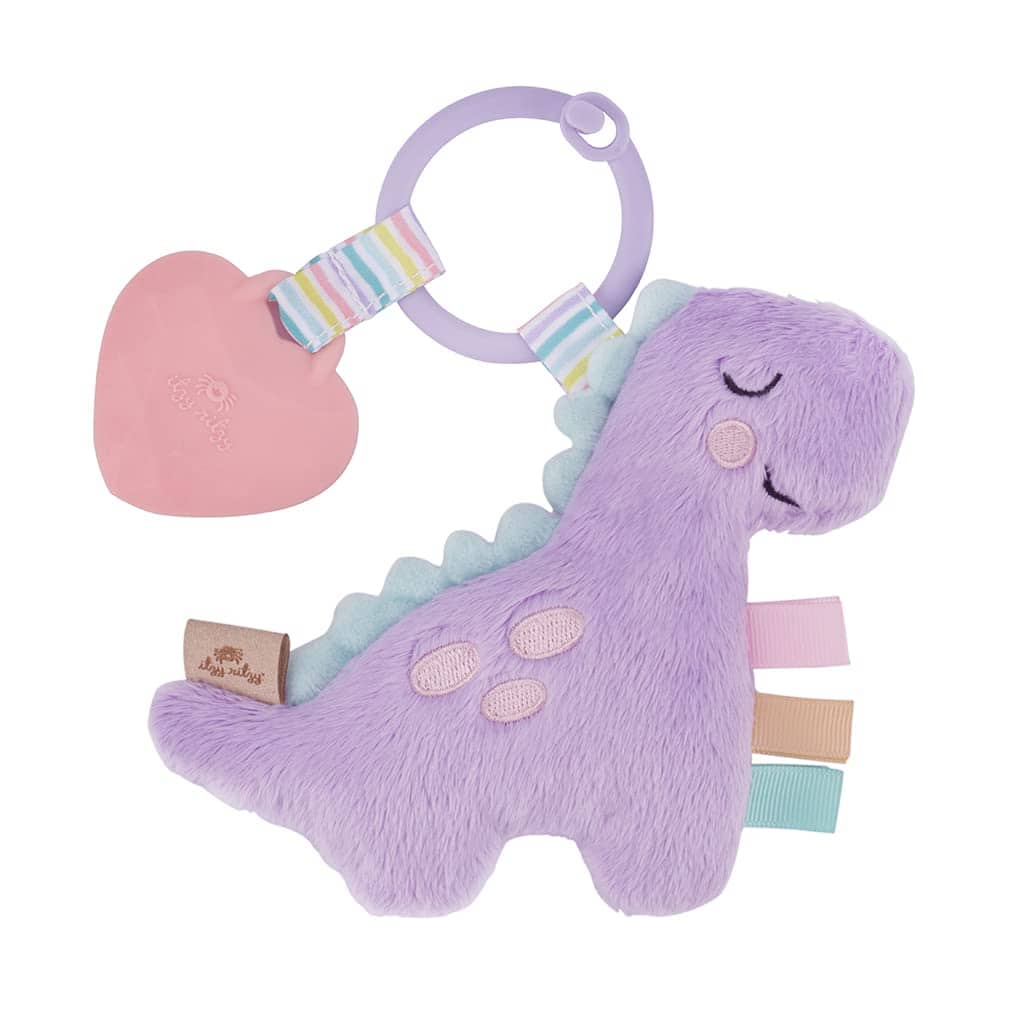 itzy ritzy pal lilac dino (1) A purple dinosaur baby toy with a heart-shaped teether and colorful ribbons, isolated on a white background.