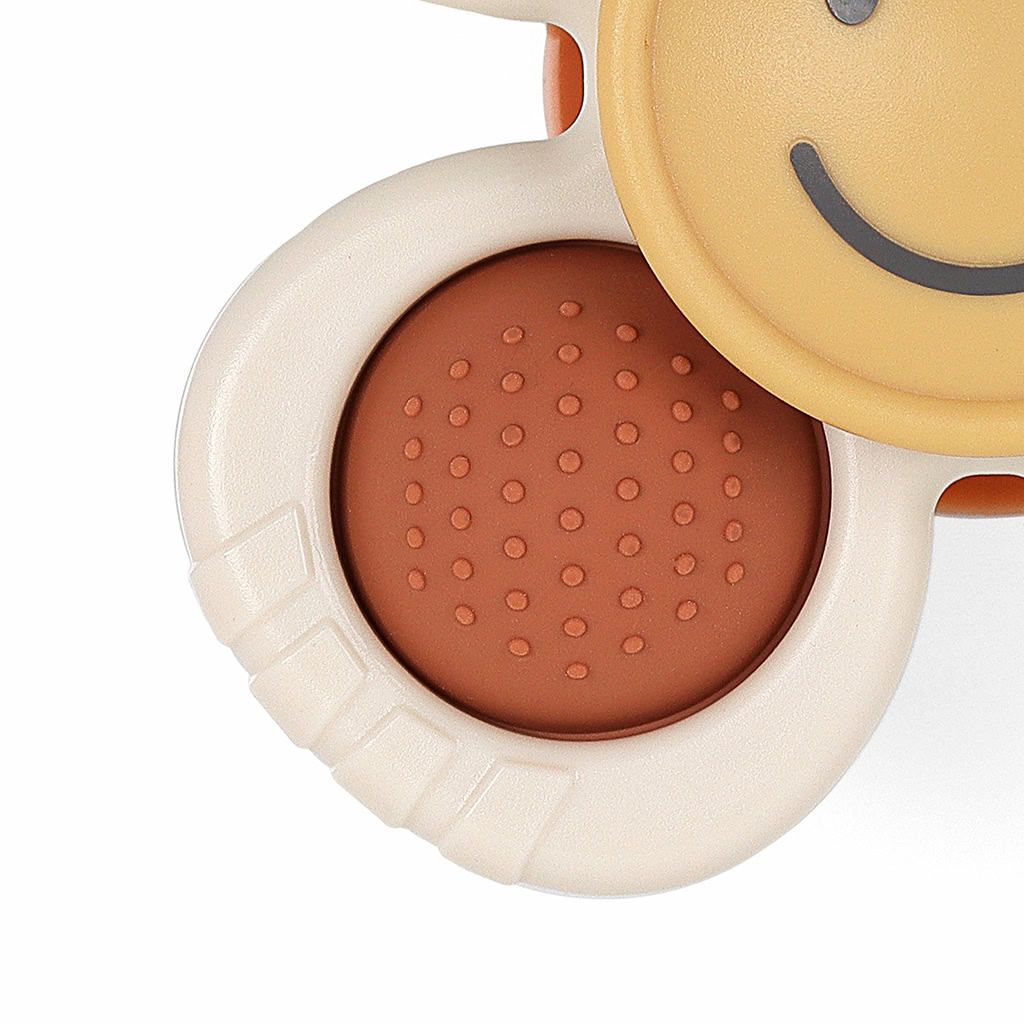 itzy-ritzy-spin8547-itzy-pop-&-whirl-smile-_5 Close-up image of a beige, round object with a smooth surface and a textured orange circle, plus a section featuring a smiling face.