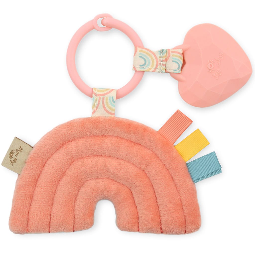 itzy-ritzy-tpl3003-itzy-pal-rainbow-3 A pink Itzy Ritzy - Itzy Pal plush baby toy shaped like a rainbow with a teething ring and various textured tags attached.