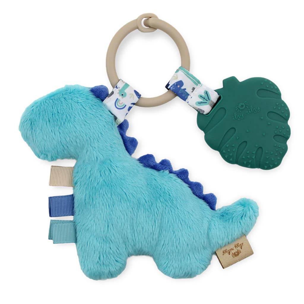 itzy-ritzy-tpl8449-itzy-pal-dino-4 A blue dinosaur-shaped Itzy Ritzy - Itzy Pal - Plush Pal Infant Toy with a silicone leaf, fabric tags, and a wooden ring on a white background.