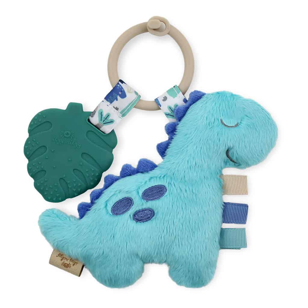 itzy-ritzy-tpl8449-itzy-pal-dino-5 A Itzy Ritzy - Itzy Pal - Plush Pal Infant Toy with Silicone Teether with tactile ribbons, a green teething leaf, and a wooden ring, isolated on a white background.